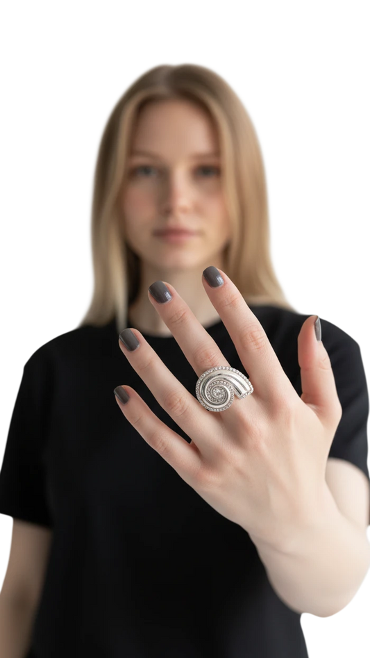 Anillo Lumaca de ErikaRivas con diseño de espiral plateada y detalles brillantes en la mano de una mujer