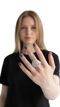 Cargar imagen en el visor de la galería, Anillo Lumaca de ErikaRivas con diseño de espiral plateada y detalles brillantes en la mano de una mujer
