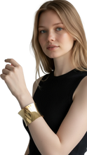 Cargar imagen en el visor de la galería, Modelo luciendo un brazalete estructurado ErikaRivas de metal dorado con acabado pulido y diseño ancho

