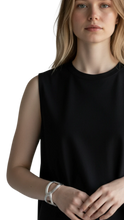 Cargar imagen en el visor de la galería, Brazalete Fiocco de ErikaRivas en plata con diseño de nudo minimalista lucido por una modelo con camiseta negra
